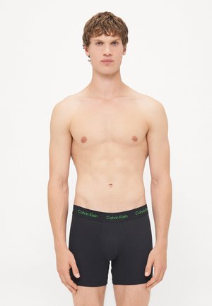 Zwarte boxershorts met een groene Calvin Klein tailleband, gemaakt van een gladde stof; aansluitend ontwerp met een opening aan de voorkant en korte pijpen.
