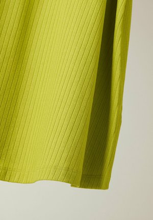 Helles grünes, geripptes Gewebe mit vertikalen Linien und einem genähten Saum, das weich vor einem neutralen Hintergrund drapiert ist.