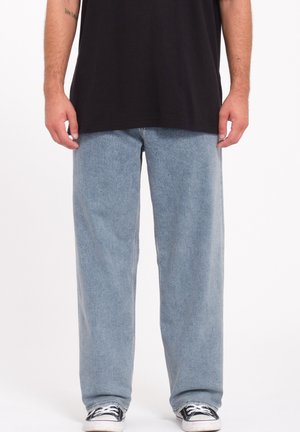 Light blue denim jeans with a straight-leg design, featuring a mid-rise waist and a faded texture, paired with black sneakers.