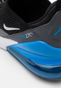 Svart och grå atletisk sko med överdel i mesh, blåaccenter och en distinkt blå luftkuddarsula. "Air 270"-logotyp synlig.