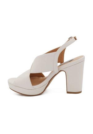 Sandalo slingback bianco in pelle con tacco a blocco, caratterizzato da cinturini che si incrociano sopra le dita e alla caviglia, completato da una soletta imbottita.