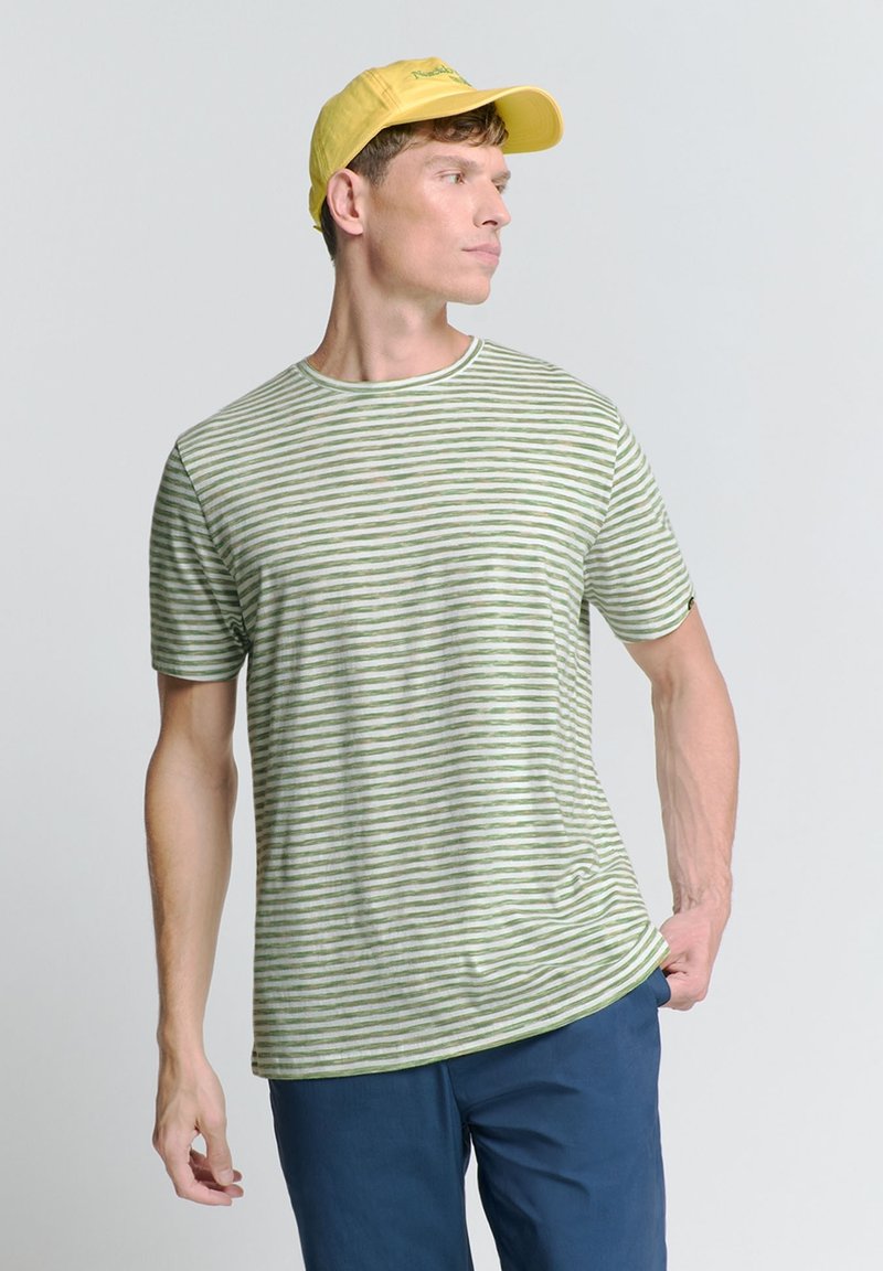 Groene en witte gestreepte t-shirt met een ronde hals en korte mouwen, gecombineerd met blauwe broek en een gele pet. Glad materiaal, casual ontwerp.