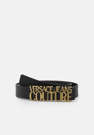 Cintura in pelle nera con grande fibbia dorata "VERSACE JEANS COUTURE" su sfondo bianco.