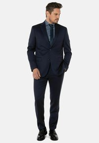Marineblauwe pak met een blazer met twee knopen en rechte broek. Draag het met een bijpassende stropdas en shirt. Fijn afgewerkt met een gladde textuur. Zwarte schoenen.