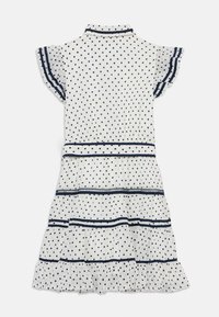 Robe blanche à pois avec des accents bleu marine, dotée de manches courtes à volants, d'un col et d'un design de jupe à plusieurs niveaux avec des rayures horizontales.