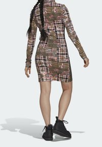 Mekko, jossa on pitkä hiha ja monivärinen ruudullinen kuosi punaisen, vihreän ja keltaisen sävyissä. Istuva malli, sivuaukot ja yhdistetty mustien nilkkasaappaiden kanssa.