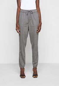 Szare joggery o zwężanym kroju z elastycznym paskiem w talii i sznurkiem do regulacji. Posiadają ściągacze na końcach nogawek oraz gładką, teksturowaną tkaninę.