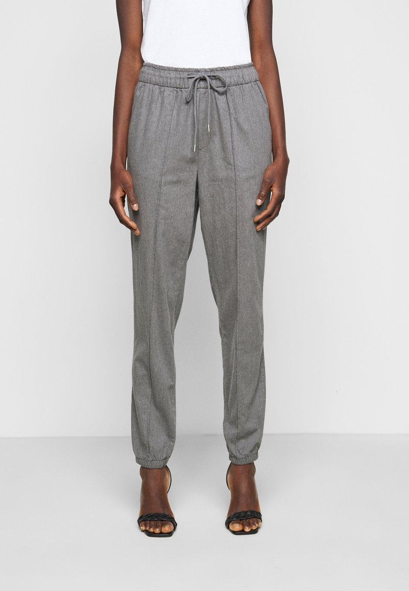 Szare joggery o zwężanym kroju z elastycznym paskiem w talii i sznurkiem do regulacji. Posiadają ściągacze na końcach nogawek oraz gładką, teksturowaną tkaninę.