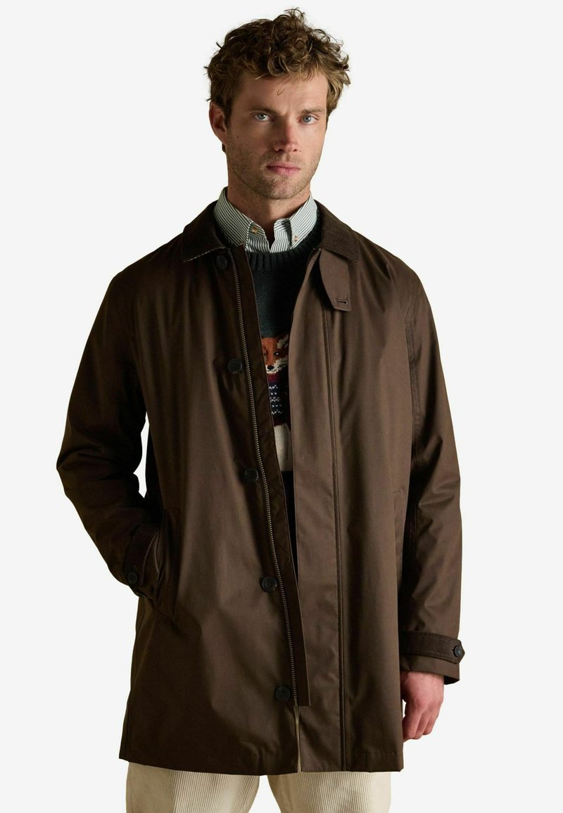 Brązowy, lekki płaszcz o prostym kroju, z zapięciem na guziki z przodu i bocznymi kieszeniami. Posiada klasyczny kołnierz oraz teksturowaną tkaninę.