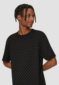 Zwarte korte mouwen t-shirt met witte stippen, ronde halslijn, ontspannen pasvorm, gemaakt van zacht katoen.