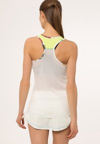 Valkoinen verkkomainen toppi, jossa on keltainen korostus kaula-aukossa, istuva muotoilu ja racerback-tyyli. Kankaan pinta on teksturoitu ja kerroksellinen ulkonäkö.