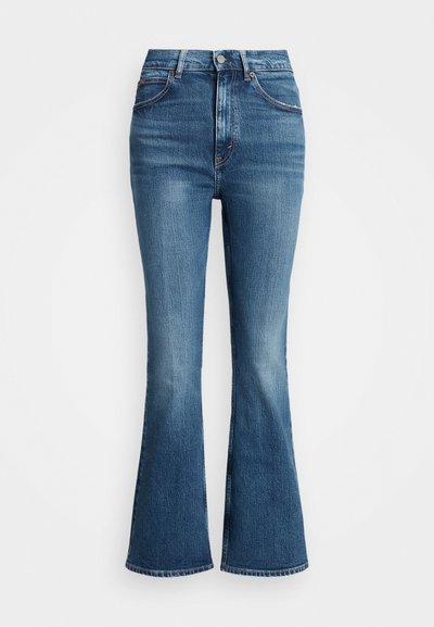 High-waisted flared jeans in medium blue denim, featuring a classic five-pocket design and contrast stitching. Edges are raw.