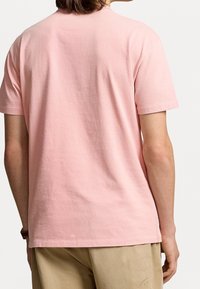 Rosa Baumwoll-T-Shirt mit kurzen Ärmeln, Rundhalsausschnitt und lockerer Passform. Sichtbare Nahtdetails am Saum und minimale Textur.