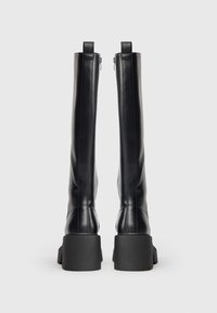 Black leather knee-high boots with a chunky platform sole, vertical stitching, and metal zipper detail at the back. Smooth texture.