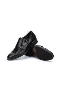 Zwarte leren schoenen met een puntige neus, dubbele gespen, gladde oppervlakte en een rubbere zool met profiel.