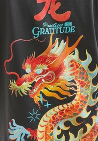 Dragon chinois rouge et orange coloré avec des accents bleus, texte accompagnant "Pratiquez la gratitude" et des caractères chinois sur un fond noir.