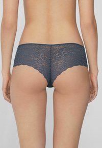 Krajkové dámské šortky v námořnické modré barvě s květinovým vzorem, s vlnkovanými okraji a průhlednou texturou, které poskytují pohodlné nošení a minimální zakrytí.