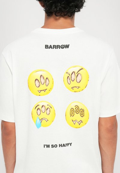 T-shirt bianco in cotone con quattro design di emoticon gialli con espressioni diverse e il testo "SONO COSÌ FELICE" sotto in nero.