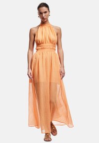 Robe maxi orange à encolure halter, fabriquée en tissu léger et froissé ; présente un corsage ajusté et une jupe fluide, avec un accent à la taille.