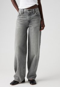 Wide-leg jeans in faded grey denim, featuring a high waist, front pockets, and contrast stitching. Finished with a raw hem.