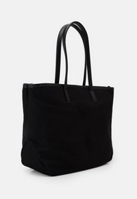 Svart canvas toteväska med släta svarta läderaccenter, rektangulär form och två långa handtag för bärande. Ren design, inga synliga mönster.