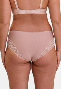 Sous-vêtements rose clair avec une texture lisse et des détails en dentelle sur les côtés, offrant un design couvrant et des bretelles réglables.