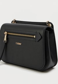 Μαύρη δερμάτινη τσάντα crossbody με δομημένο σχέδιο, χρυσό φερμουάρ και λογότυπο DKNY. Διαθέτει αποσπώμενο λουρί και υφή.