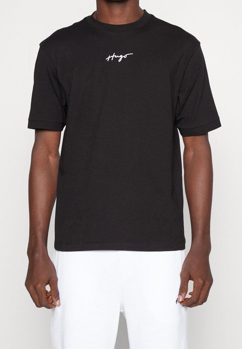 T-shirt nera a maniche corte con scollo rotondo, con logo testuale "Hugo" bianco sul petto. Realizzata in morbido cotone.