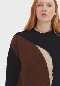 Strickpullover mit einem Farbblockdesign in Dunkelblau, Braun und Creme, mit einer strukturierten Oberfläche und Rundhalsausschnitt.