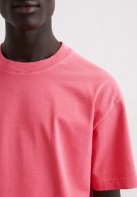 Korte mouwen ronde hals t-shirt in een levendige koraalkleur, gemaakt van zacht katoen met een gladde textuur en ribbelkraagdetail.