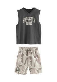 Grijs mouwloos topje met de tekst "BROOKLYN NEW YORK CITY 1992", gecombineerd met beige camouflage shorts met een elastische tailleband en trekkoord.
