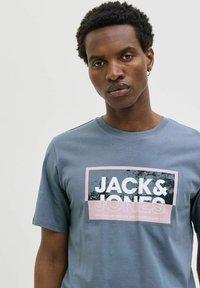 Grijze katoenen T-shirt met een vierkante grafische print met de tekst "JACK & JONES" in wit en roze, korte mouwen en ronde hals.