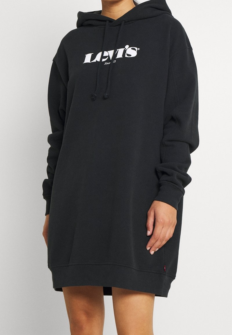 Robe à capuche noire en tissu doux, avec un logo imprimé sur le devant, une capuche à cordon, des manches longues et une coupe décontractée.
