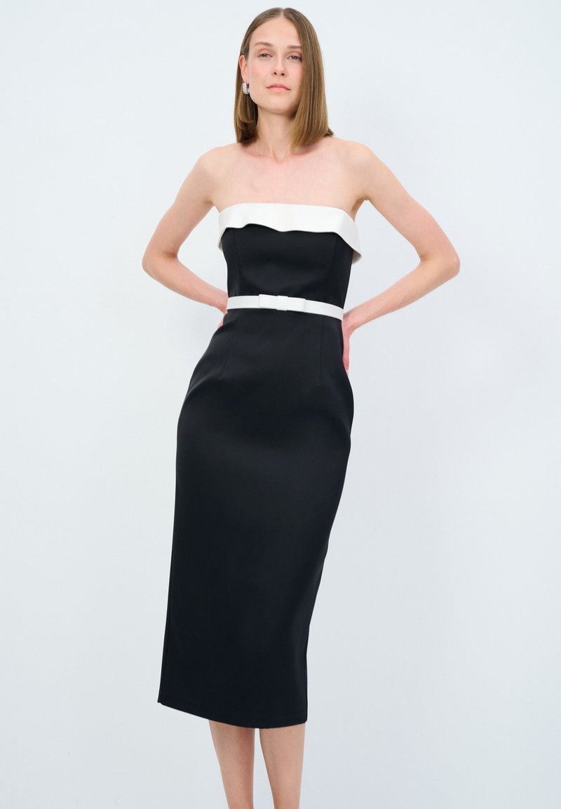 Schwarzes trägerloses Kleid mit einem weißen Rüschenausschnitt, tailliertem Schnitt und einem gerafften weißen Gürtel. Glattes, leichtes Material mit einer knielangen Länge.