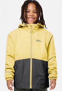 Giacca impermeabile gialla e nera con zip frontale, cappuccio regolabile, polsini elasticizzati e dettaglio con logo sul petto. Texture liscia.