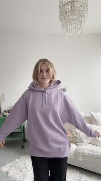 Oversized lavendelfärgad hoodie med dragsko, långa ärmar och mjuk textur. Bärs med svarta byxor, visas mot en ljus bakgrund.