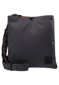 Šedá tkaninová ramenní taška s oranžovým horním lemem, nastavitelným popruhem a černou logem nášivkou. Disponuje zipovým uzávěrem a hladkým povrchem.