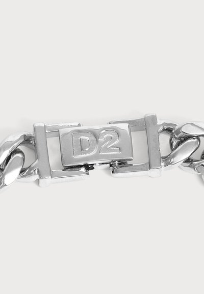 Gros plan sur un fermoir de bracelet chaîne en métal argenté gravé des lettres et du numéro D2.