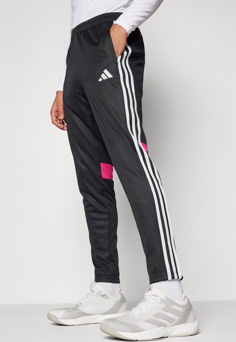 Pantalons de sport noirs avec des rayures blanches et un accent rose. Fabriqués dans un matériau lisse avec une taille élastique et des poches latérales.