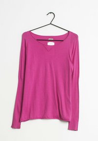 Różowy sweter z długim rękawem o prążkowanej fakturze i dekolcie w kształcie V. Wiszący na czarnym wieszaku na białym tle. Metka przymocowana przy dekolcie.