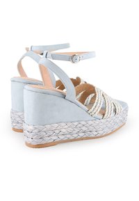 Sandalias de cuña en ante azul claro, con detalles trenzados y suela de yute tejida, con correas de tobillo ajustables.