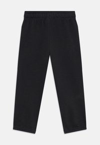 Pantalons de sport noirs en tissu doux et extensible. Dotés d'une taille élastique et de jambes fuselées. Pas de motifs visibles ni d'accents en métal.