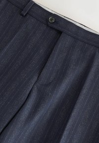 Tengerészkék csíkozott nadrág texturált anyagból, gombos záródással és sima elülső kialakítással. A függőleges csíkok fokozzák a vizuális érdekességet.