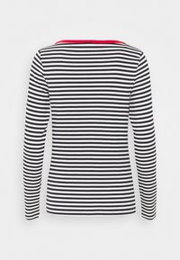 Långärmad topp med ett svart och vitt randigt mönster, en enfärgad röd halsringning och en figurnära design. Tillverkad av ett mjukt, elastiskt tyg.