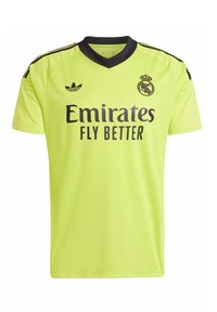 Camisa deportiva verde con cuello en V, detalles en negro y el logo de un club de fútbol. "Emirates FLY BETTER" impreso de manera prominente en la parte frontal.
