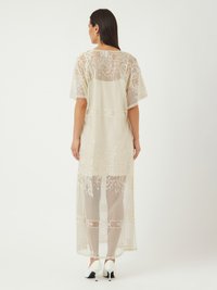 Kimono long, couleur crème, en dentelle avec des motifs floraux et paisley, à manches courtes et à design transparent. Présente une coupe droite jusqu'à la cheville.