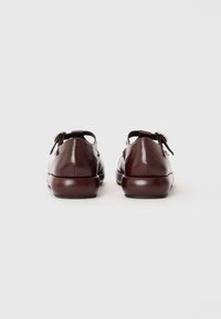 Bordowe skórzane buty o gładkim wykończeniu, zaokrąglonym nosku, z wycięciem z tyłu oraz ozdobnym kokardkowym detalem na każdym obcasie.