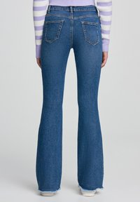 Jeans svasati blu in denim, con orlo sfrangiato, due tasche posteriori e un design a vita alta. Texture liscia in tutta la superficie.