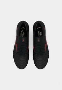 Melna un sarkana Mizuno futbola zābaku pāris skatīts no augšas uz balta fona.