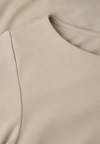 Beiges Stoffoberteil mit glatter Textur, runder Halslinie und kurzen Ärmeln. Einfaches Design mit dezenten Nähdetails.